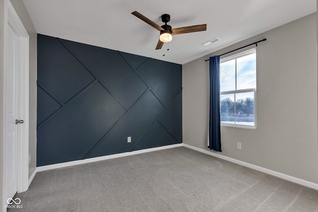 carpeted spare room featuring a ceiling fan, visible vents, and baseboards