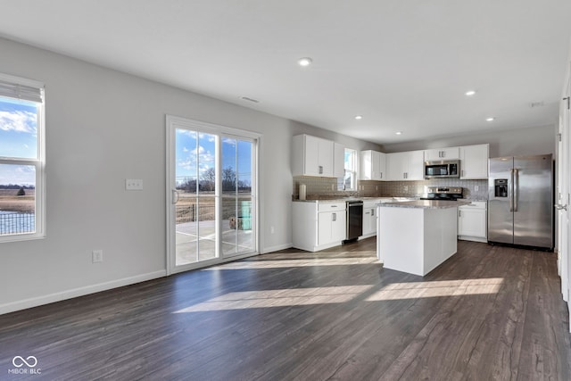 kitchen featuring dark wood-type flooring, a center island, stainless steel appliances, decorative backsplash, and baseboards