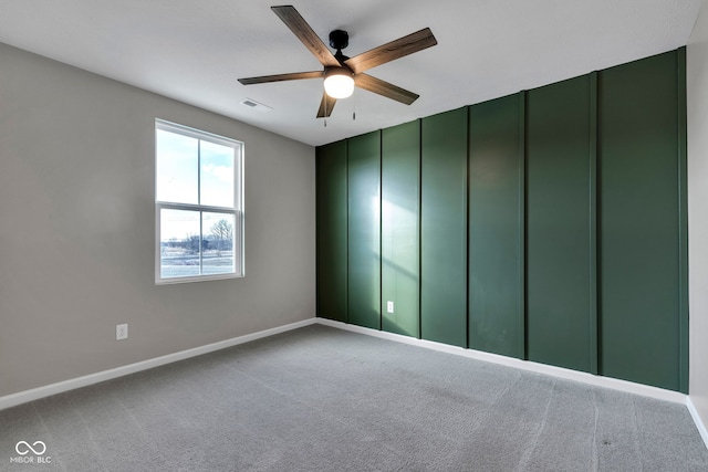 carpeted empty room featuring visible vents, baseboards, and a ceiling fan