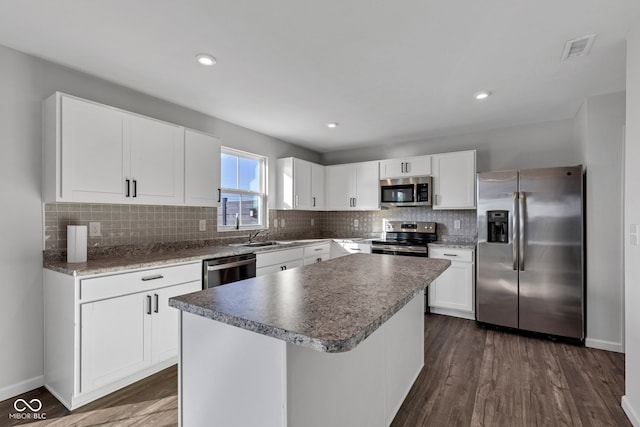 kitchen featuring visible vents, backsplash, dark wood finished floors, a center island, and stainless steel appliances