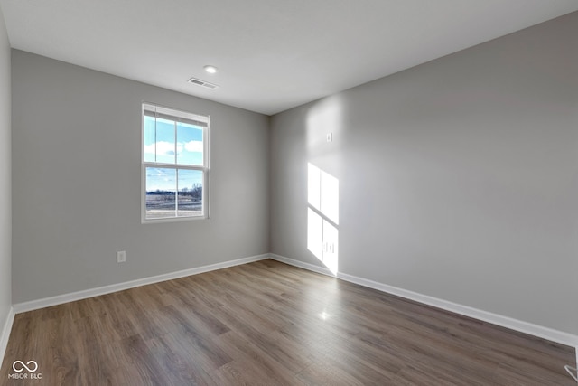 empty room with visible vents, baseboards, and wood finished floors