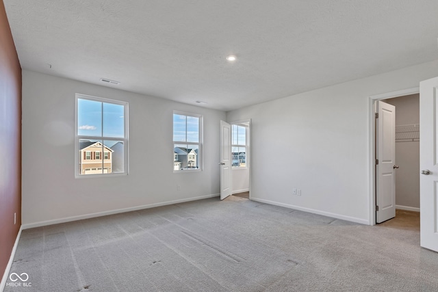 unfurnished room featuring visible vents, a textured ceiling, baseboards, and carpet floors