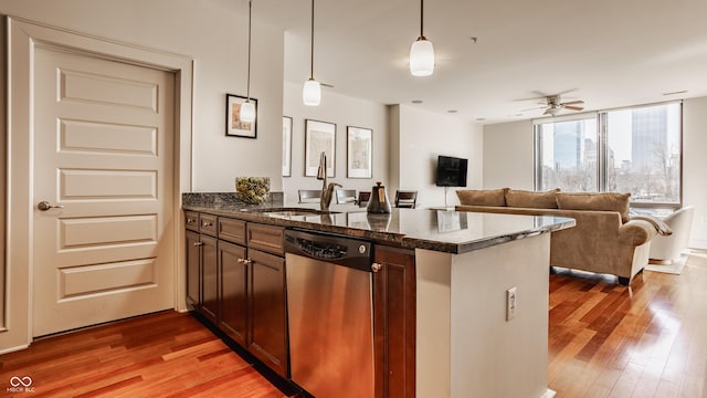 kitchen featuring a sink, open floor plan, a peninsula, light wood finished floors, and dishwasher