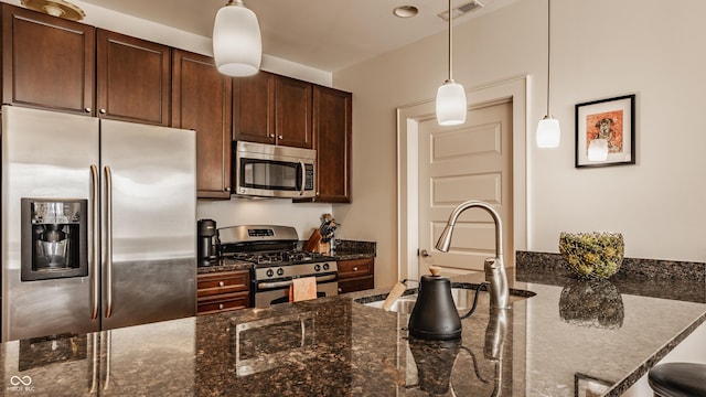 kitchen with visible vents, dark stone countertops, appliances with stainless steel finishes, and pendant lighting