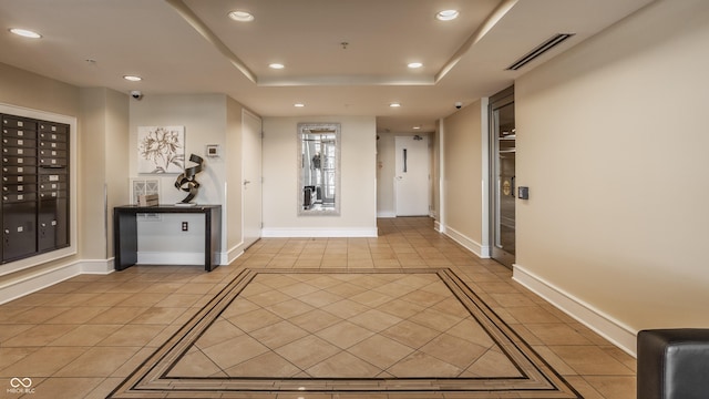 hallway with visible vents, mail area, a tray ceiling, light tile patterned floors, and recessed lighting