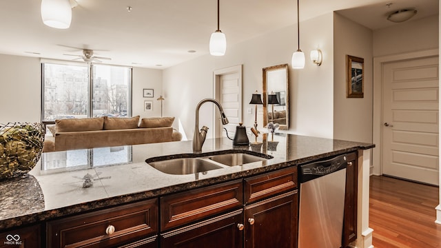 kitchen featuring wood finished floors, a sink, pendant lighting, dishwasher, and open floor plan