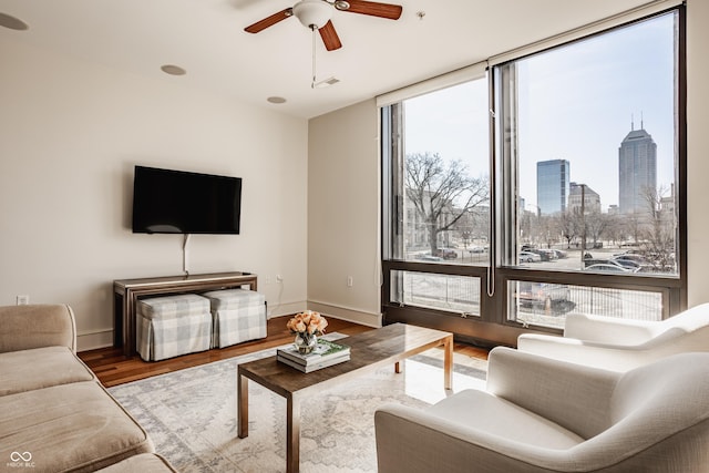 living room with visible vents, wood finished floors, floor to ceiling windows, baseboards, and ceiling fan