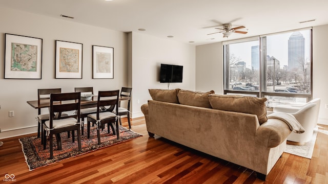 living area with visible vents, a ceiling fan, and wood finished floors