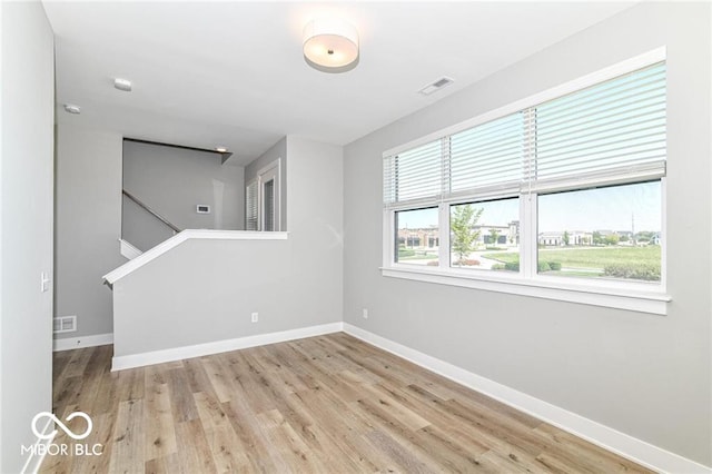 unfurnished room featuring visible vents, baseboards, and wood finished floors