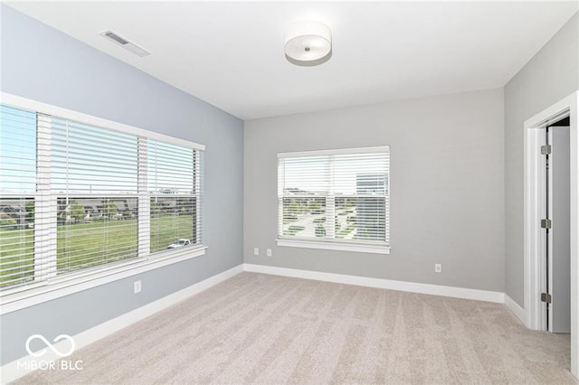 unfurnished room featuring light colored carpet, visible vents, and baseboards