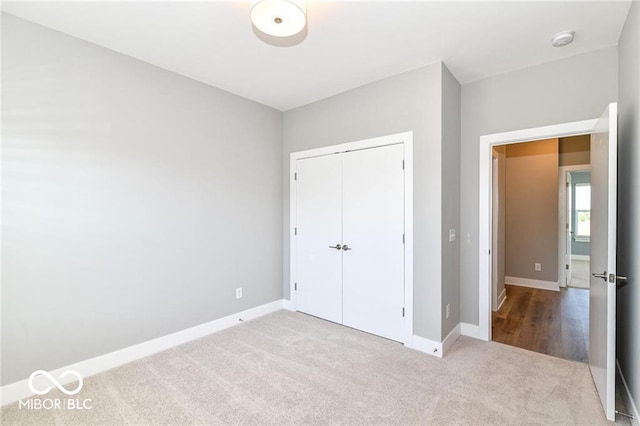 unfurnished bedroom with a closet, carpet flooring, and baseboards