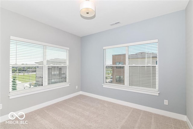 carpeted spare room featuring baseboards and visible vents