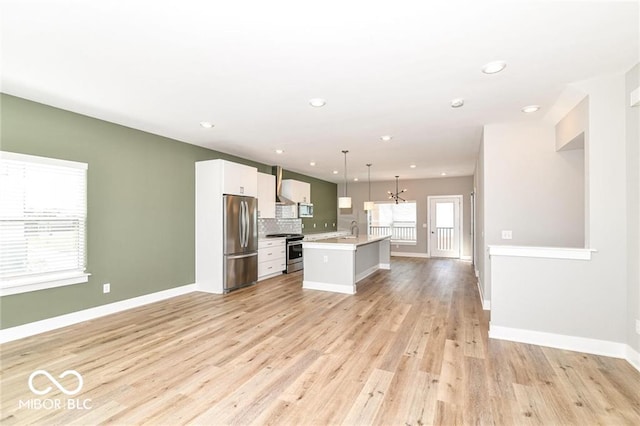 kitchen featuring light wood-type flooring, open floor plan, appliances with stainless steel finishes, and a kitchen island with sink