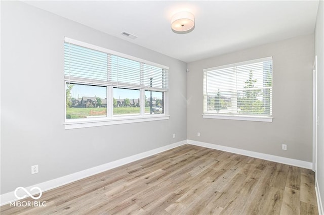 unfurnished room with a wealth of natural light, visible vents, and baseboards