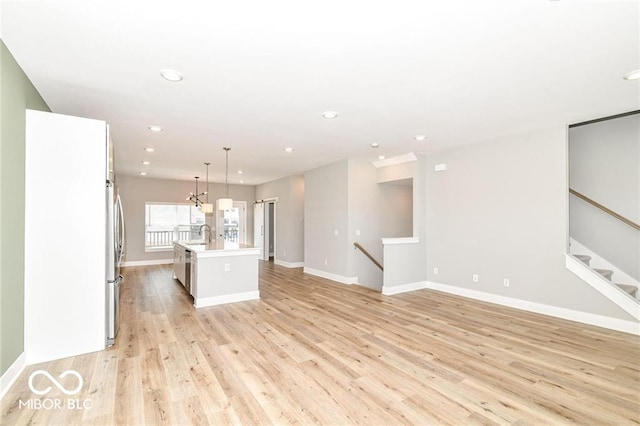 interior space with light wood finished floors, an island with sink, white cabinetry, recessed lighting, and light countertops