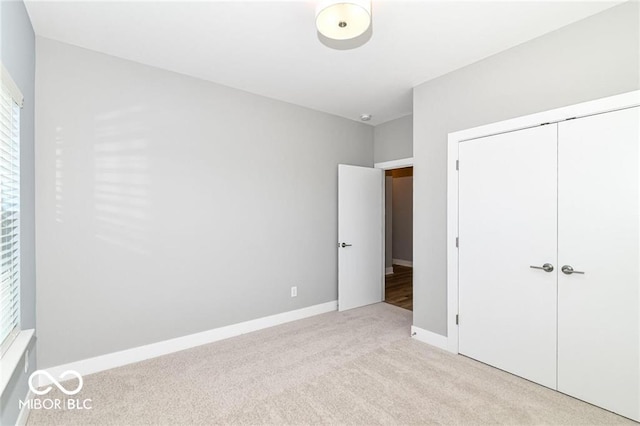 unfurnished bedroom featuring baseboards, a closet, and light carpet