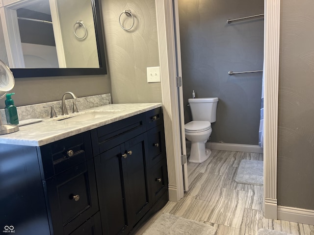 bathroom featuring vanity, toilet, and baseboards