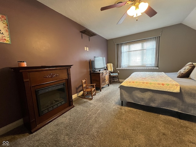 bedroom with a glass covered fireplace, carpet, baseboards, ceiling fan, and vaulted ceiling