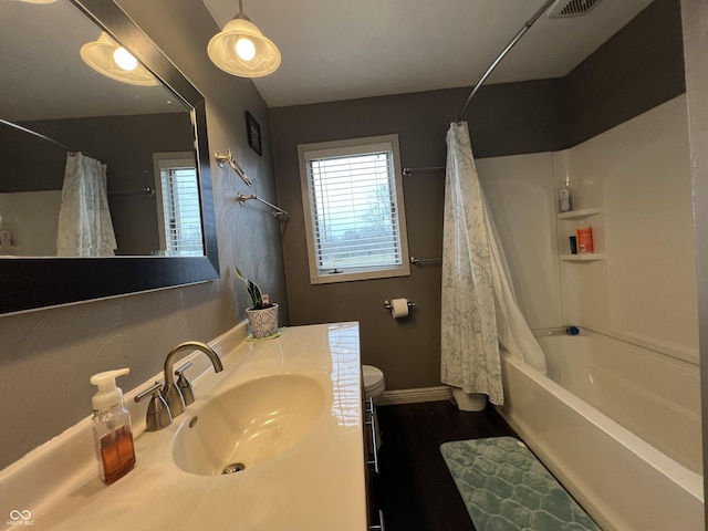 full bath featuring toilet, wood finished floors, shower / tub combo, baseboards, and vanity