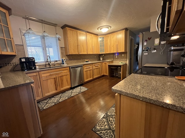 kitchen featuring backsplash, glass insert cabinets, dark wood-style floors, stainless steel appliances, and a sink