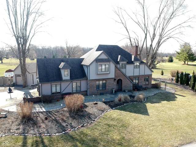 view of front facade with stucco siding, roof with shingles, a chimney, and a front yard