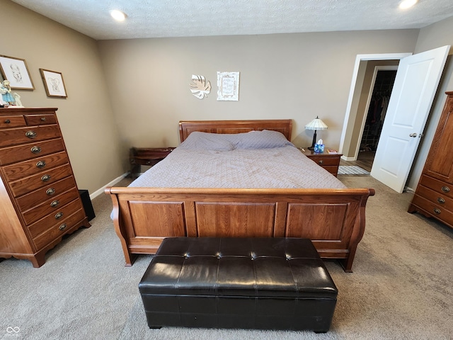 bedroom with baseboards, light colored carpet, and a textured ceiling