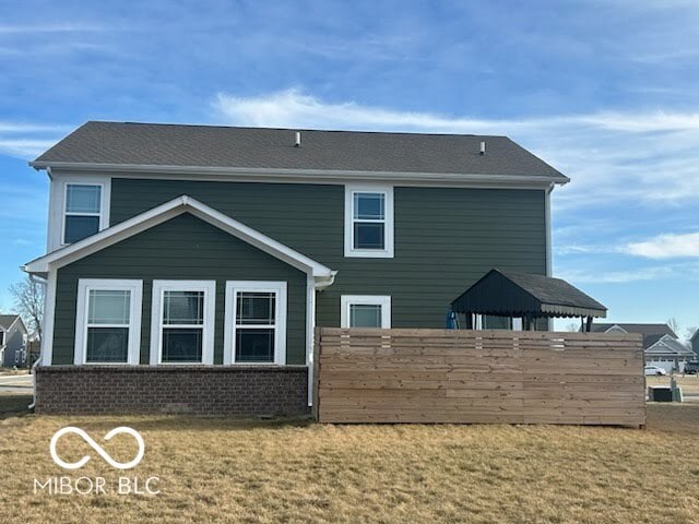 back of property with a gazebo, a lawn, and brick siding