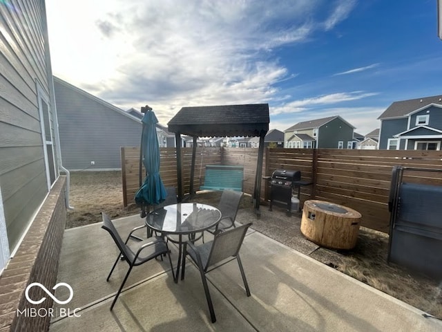 view of patio with area for grilling, outdoor dining area, fence, and a residential view