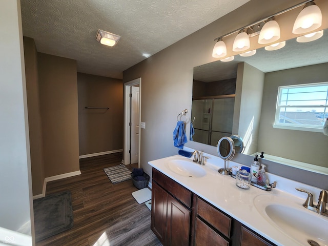 full bath featuring double vanity, a shower stall, wood finished floors, and a sink