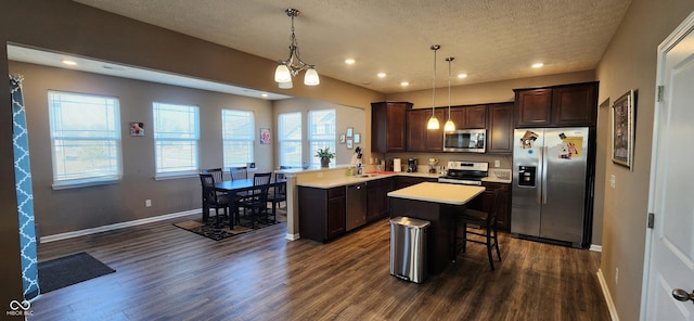 kitchen with dark wood finished floors, light countertops, dark brown cabinetry, and stainless steel appliances