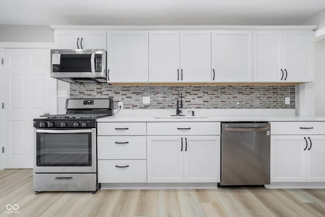 kitchen with a sink, stainless steel appliances, white cabinetry, and light countertops