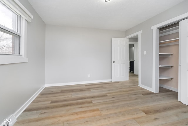 unfurnished bedroom featuring baseboards, light wood-type flooring, and a closet