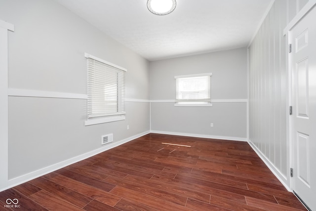 unfurnished room featuring visible vents, baseboards, and wood finished floors