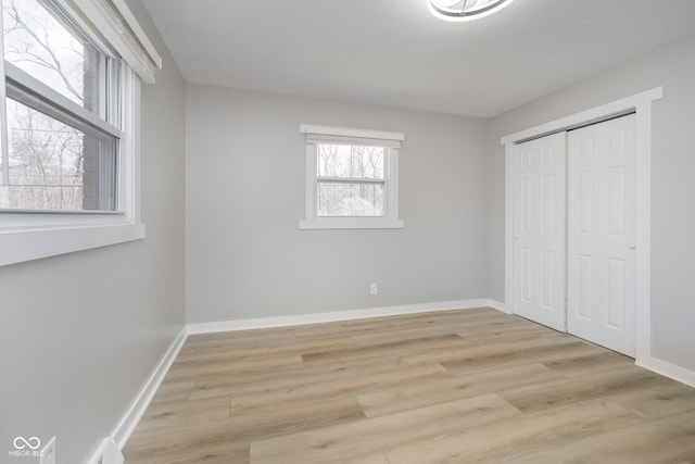 unfurnished bedroom with a closet, light wood-style flooring, and baseboards