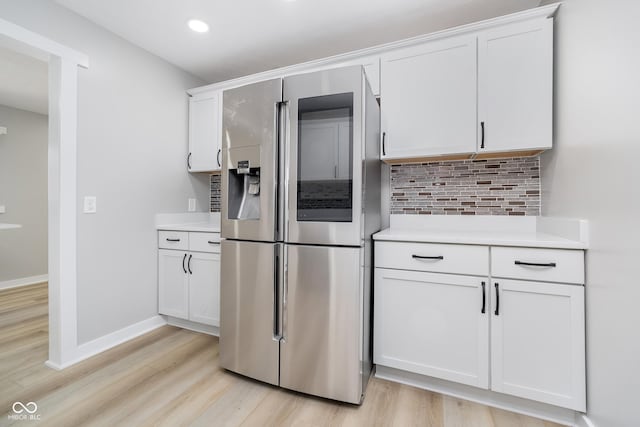 kitchen with decorative backsplash, white cabinetry, stainless steel fridge with ice dispenser, and light countertops