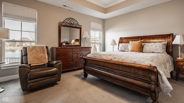 bedroom with visible vents, a tray ceiling, crown molding, baseboards, and light colored carpet