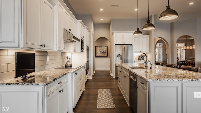 kitchen with dark wood-style flooring, arched walkways, a sink, appliances with stainless steel finishes, and under cabinet range hood