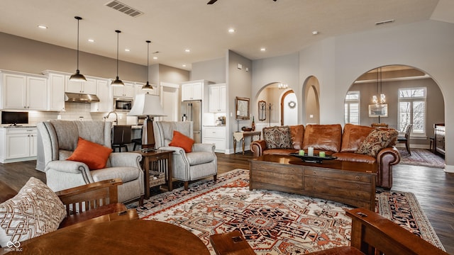 living area featuring arched walkways, visible vents, and high vaulted ceiling