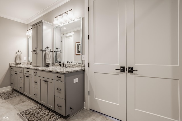 bathroom with a sink, baseboards, ornamental molding, and double vanity