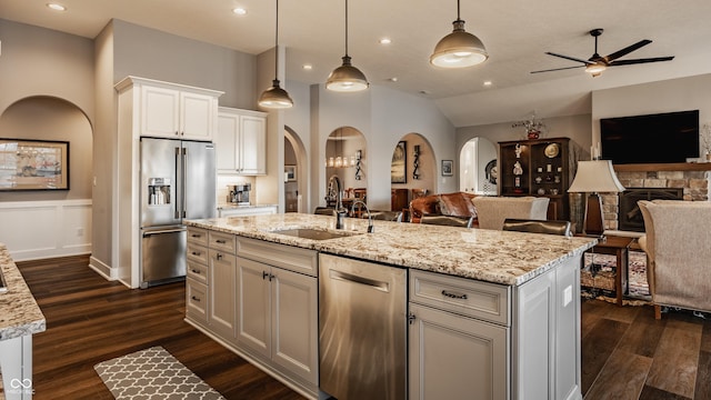 kitchen with open floor plan, arched walkways, appliances with stainless steel finishes, and a sink