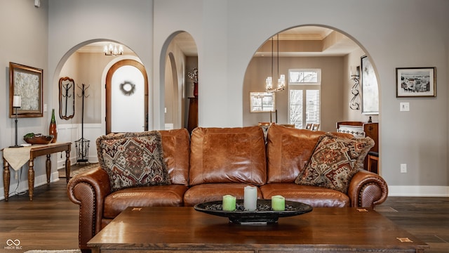 living area with baseboards, an inviting chandelier, dark wood-style flooring, and crown molding