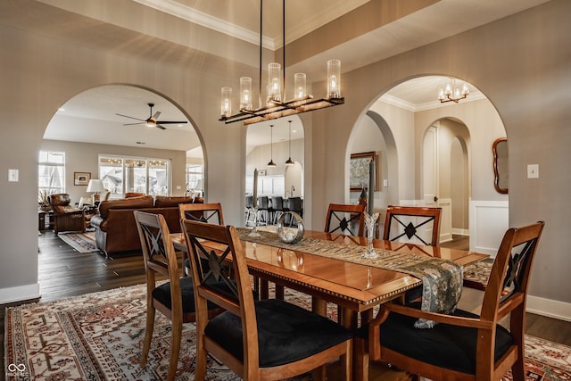 dining room featuring dark wood finished floors, arched walkways, crown molding, and a tray ceiling