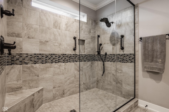 bathroom with baseboards, ornamental molding, and a tile shower