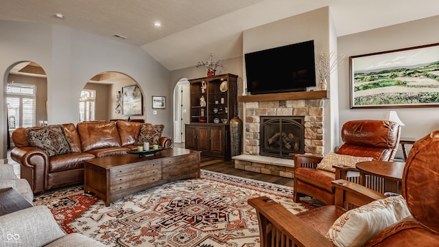 living room featuring visible vents, wood finished floors, recessed lighting, a stone fireplace, and vaulted ceiling