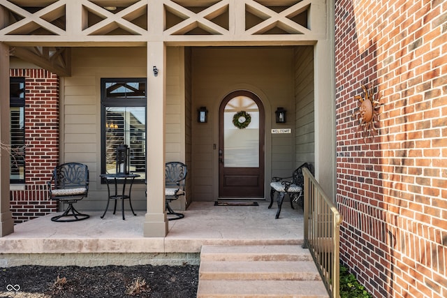 view of exterior entry featuring brick siding and covered porch