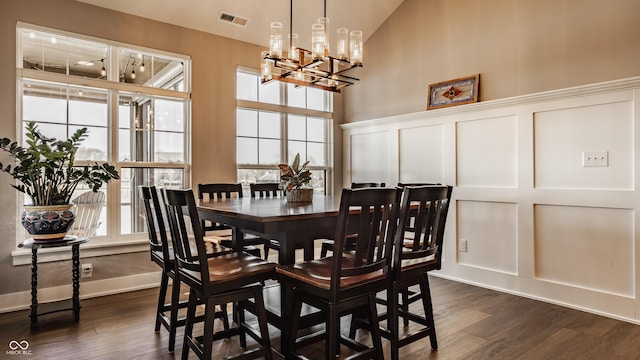 dining room featuring dark wood finished floors, a decorative wall, a notable chandelier, and visible vents