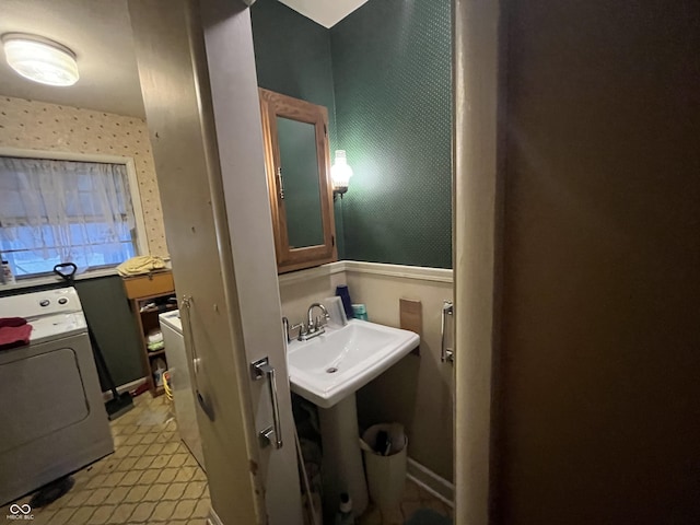 bathroom with wallpapered walls, washer / clothes dryer, and a sink