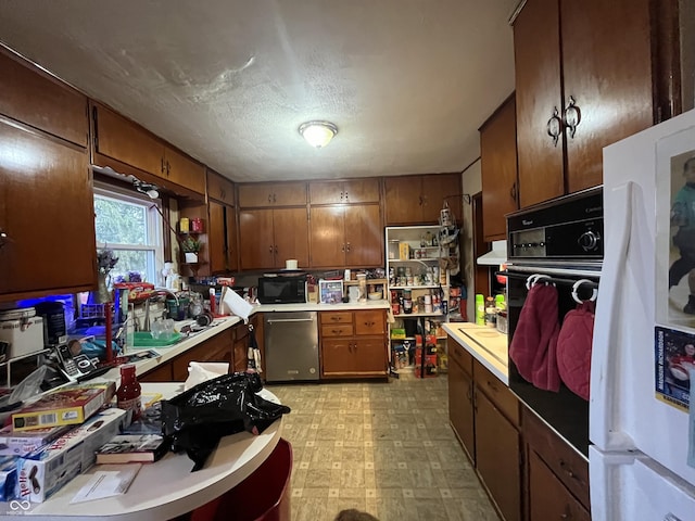 kitchen with black appliances, a sink, brown cabinetry, light countertops, and light floors