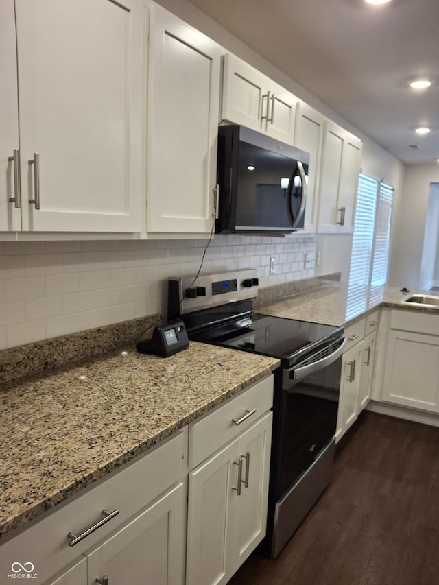 1974 Ralston Ave, Indianapolis, IN 46218 - kitchen with black microwave, stainless steel electric range oven, white cabinets, dark wood finished floors, and recessed lighting