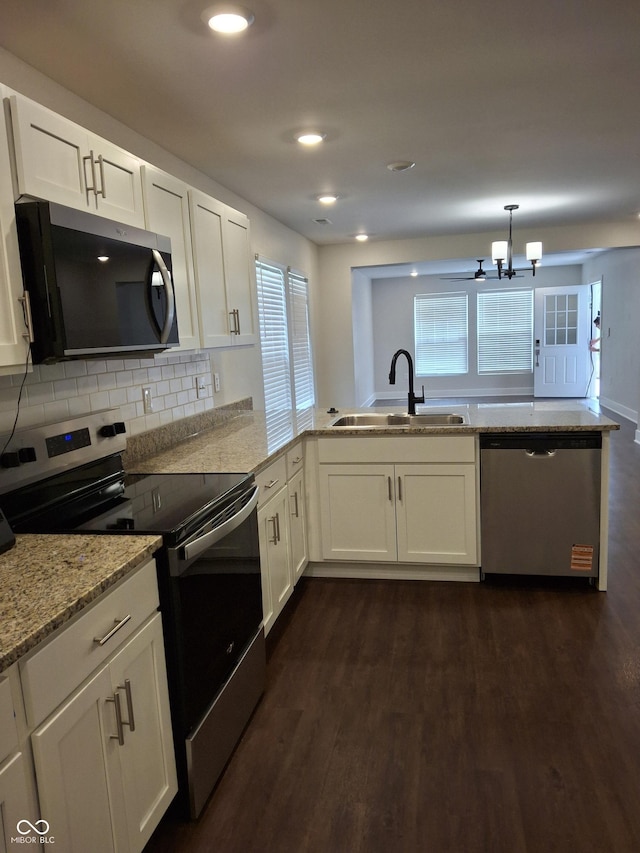 1974 Ralston Ave, Indianapolis, IN 46218 - kitchen with appliances with stainless steel finishes, a peninsula, a chandelier, dark wood finished floors, and white cabinetry